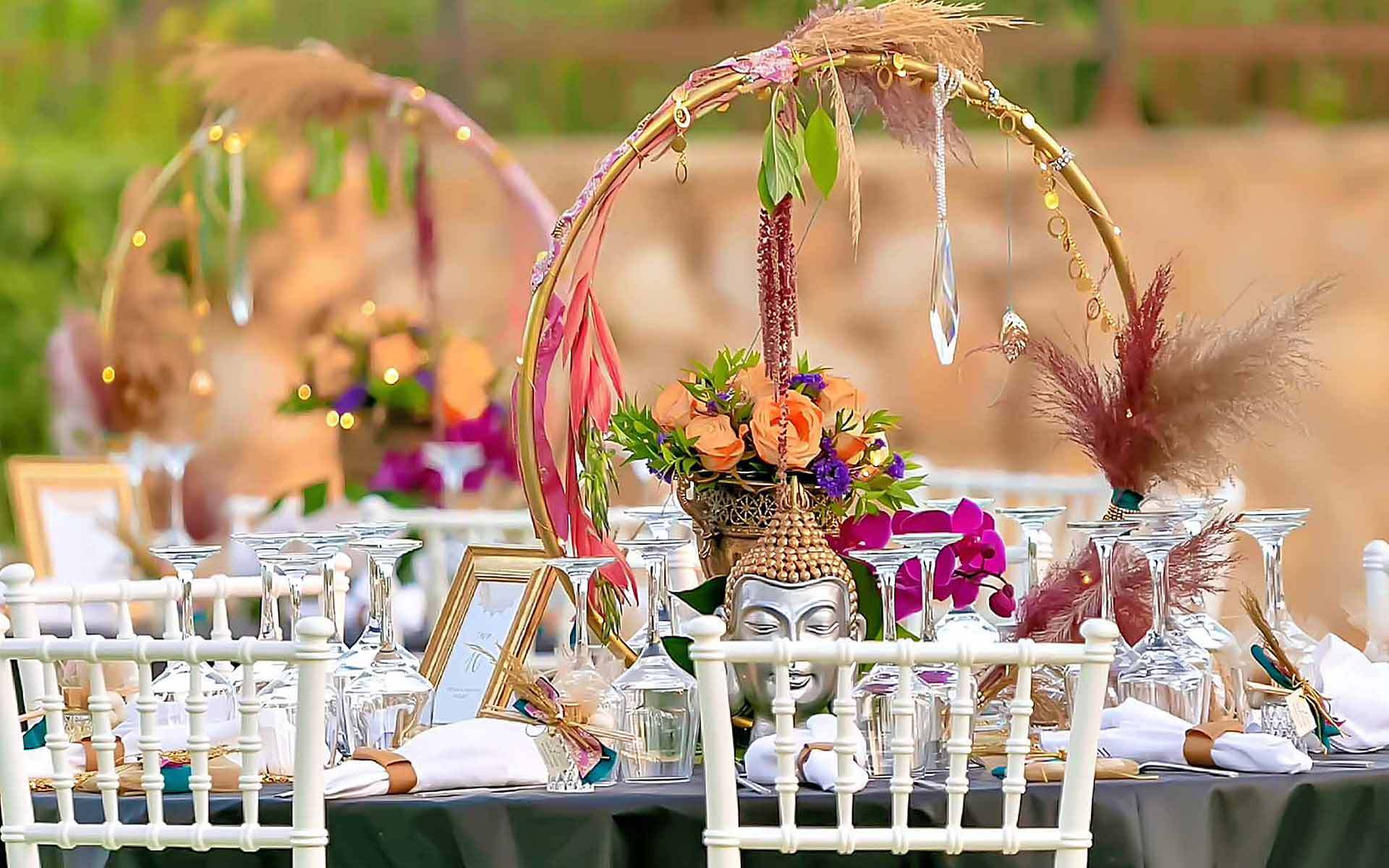 The circle of life decorated with pampas grass and natural roses used as a centerpiece alongside a gold urn and decorative Buddha figure inspired by the East culture