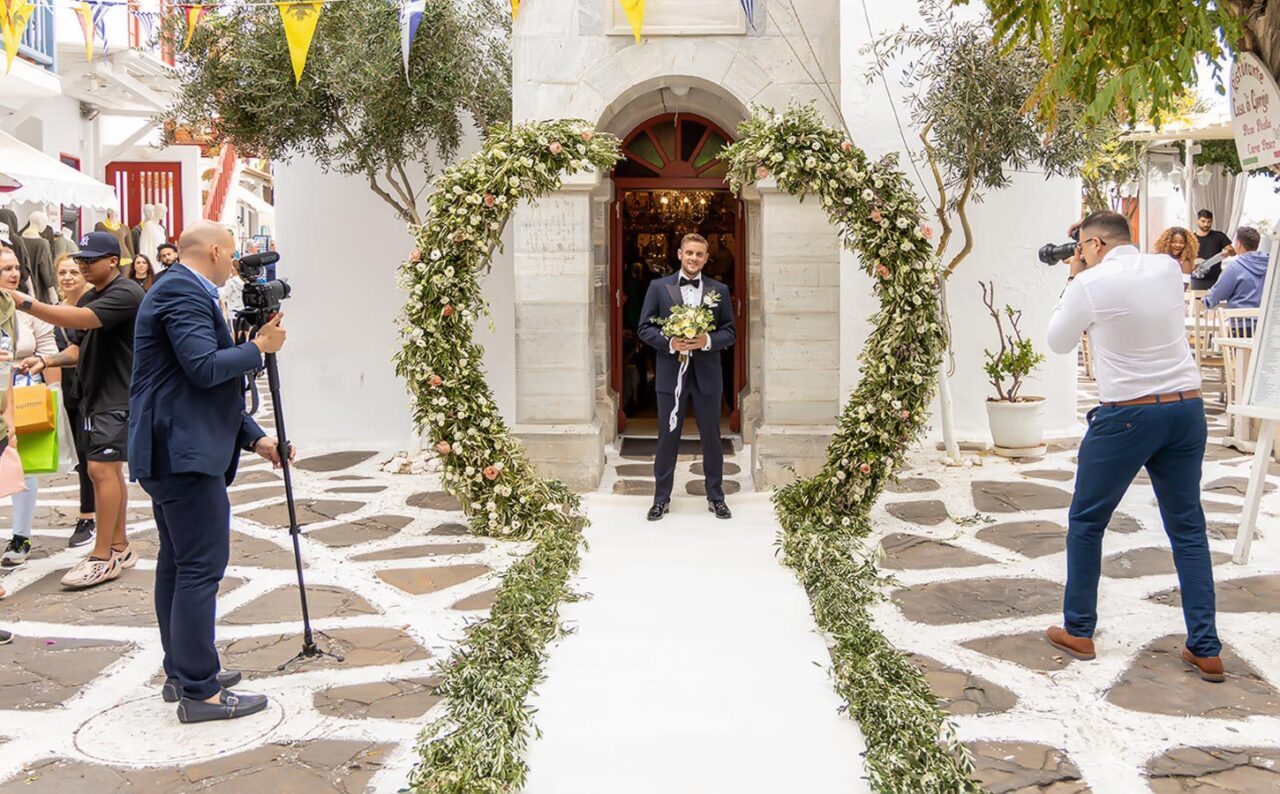 Γαμήλιος προορισμός Μύκονος 4 Εντυπωσιακή είσοδος γαμπρού στο κέντρο της Μυκόνου, μέσα από καταπράσινη αψίδα ελιάς και λουλουδιών.