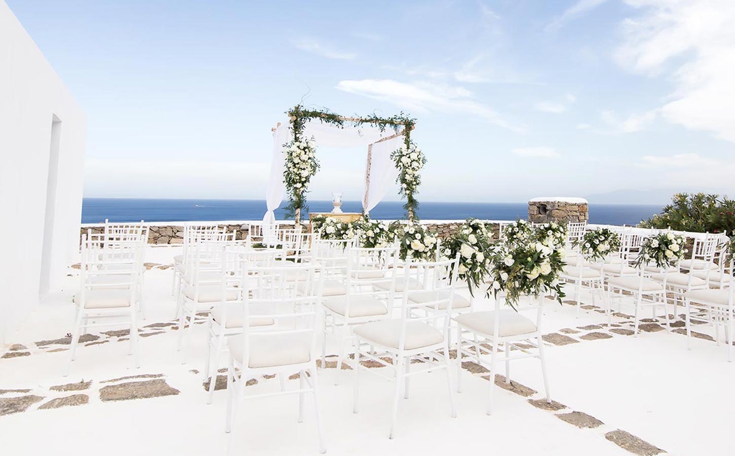 Χώρος τελετής έτοιμος να υποδεχτεί το ζευγάρι, με minimal λευκή αισθητική από την Rogdaki Events