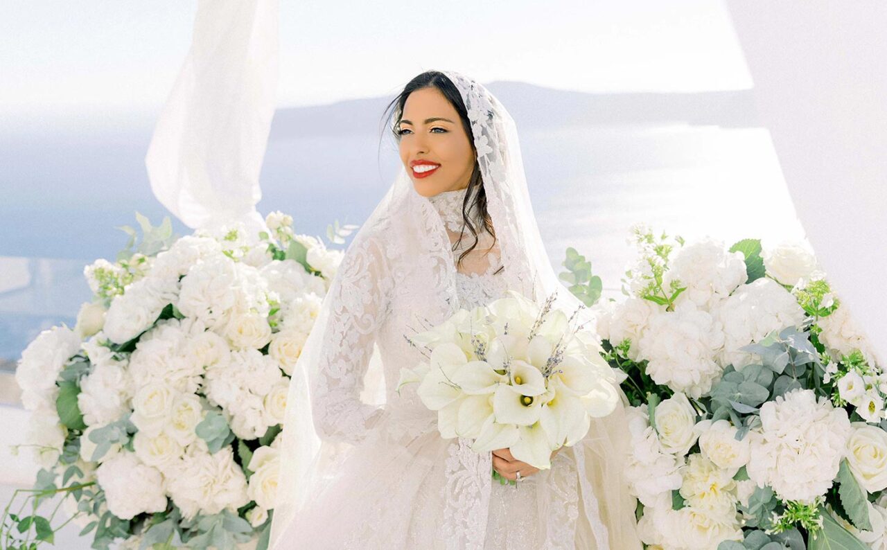 Luxury bridal portrait surrounded by white florals at a refined Santorini wedding celebration.