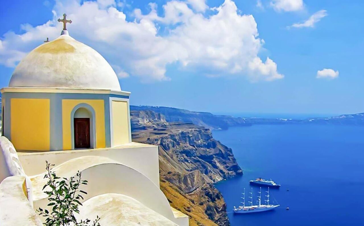 Παραδοσιακό ελληνικό εκκλησάκι πάνω από τη θάλασσα, ιδανικό φόντο για γαμήλια τελετή στη Σαντορίνη.