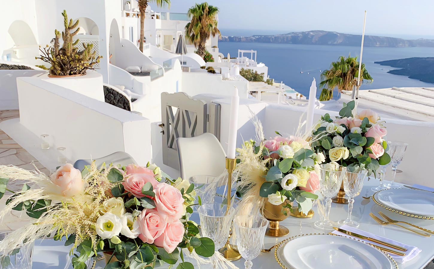 Γάμος στη Σαντορίνη με βραβευμένη εταιρεία οργάνωσης 3 Ρομαντικό τραπέζι δεξίωσης με παστέλ λουλούδια και φόντο την καλντέρα της Σαντορίνης.