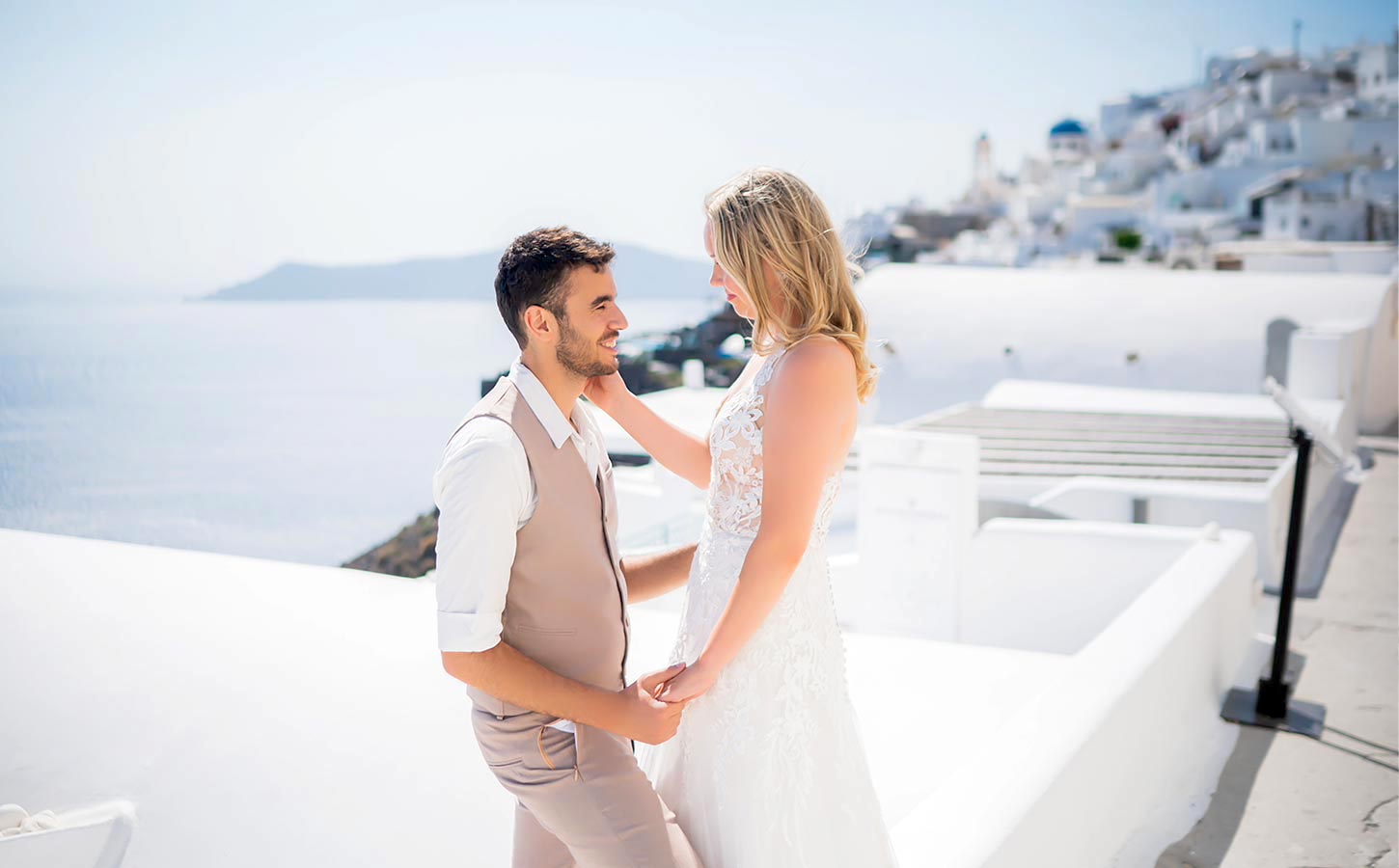 Γάμος στη Σαντορίνη με βραβευμένη εταιρεία οργάνωσης 4 Τρυφερή στιγμή ανάμεσα στο ζευγάρι σε ταράτσα με θέα στο Αιγαίο, στη Σαντορίνη.