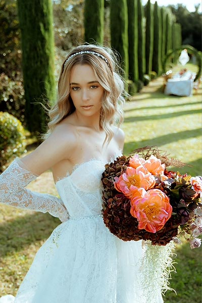 Bride in a Garden Setting Holding a Floral Bouquet by Rogdaki Events
