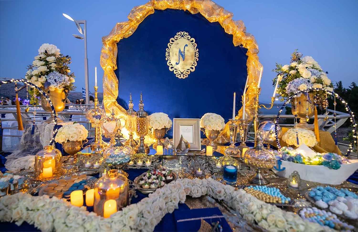 A blue and gold wishbook table set up with natural flower arrangements and candle lighting by Diamond Events