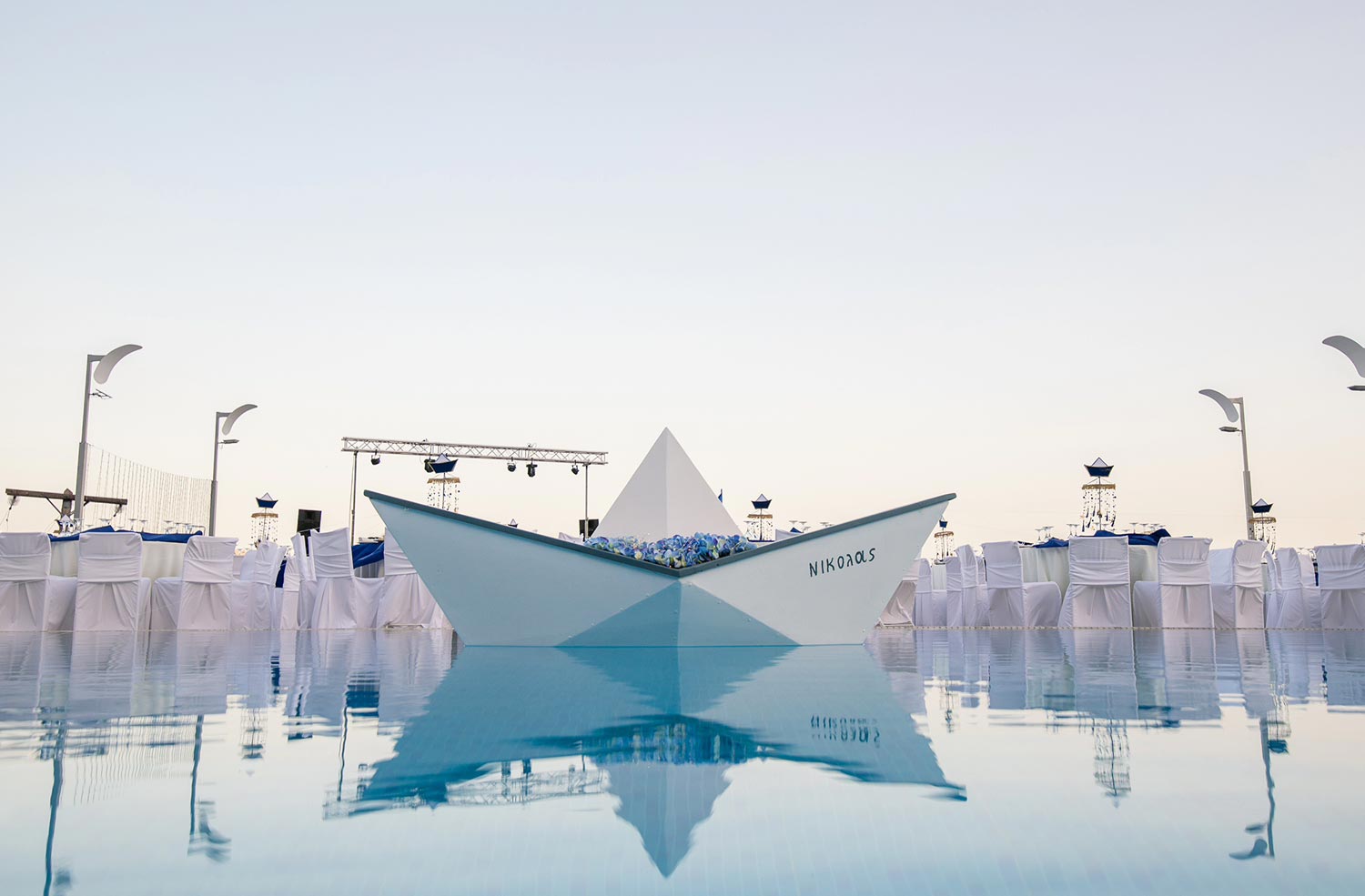 A custom made life size boat named Nicholas, after the baptized baby, placed inside the pool and decorated with blue hydrangeas by Rogdaki Events.