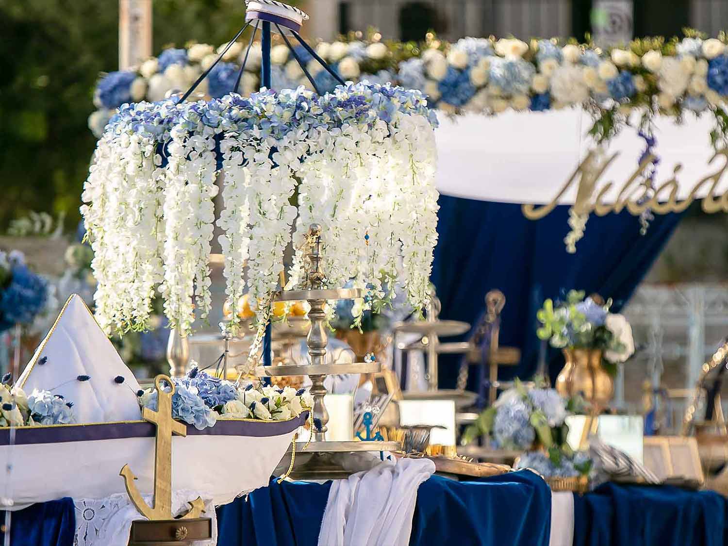 A magestic carousel full of natural flowers adding a touch of luxury in a white and blue navy themed baptism