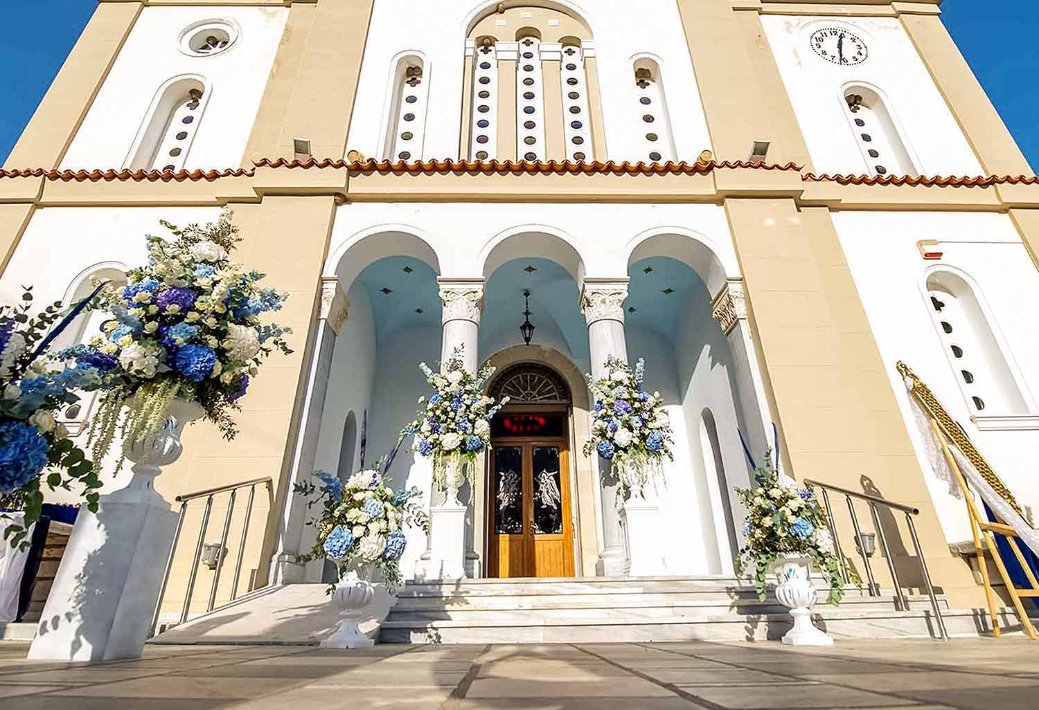 A magestic entrance for the church with white urns decorated with impressive flower arangements