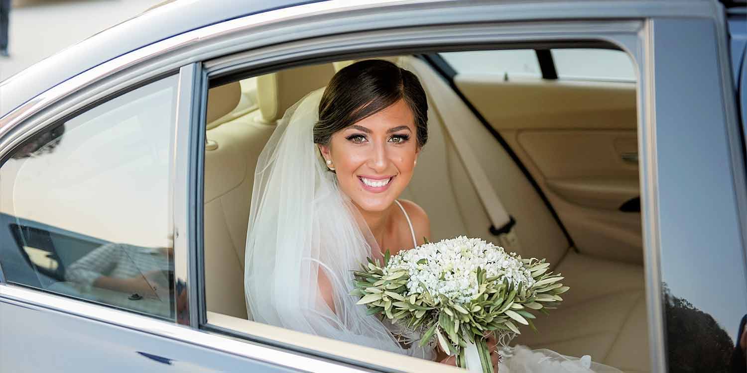 Gorgeous bride Giorgina with beautiful smile is sitting in wedding car