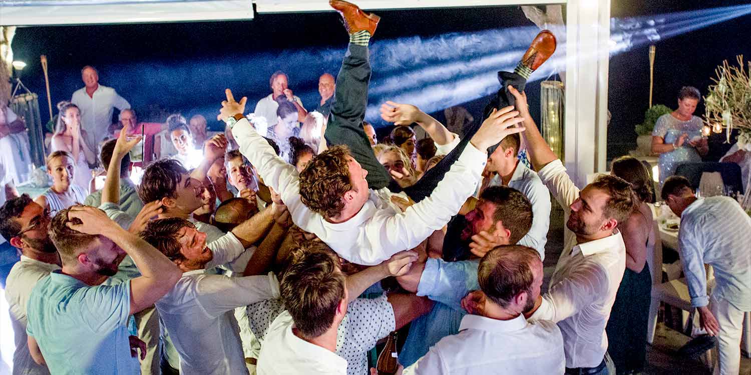 Groomsmen throwing groom into air at a Destination Wedding