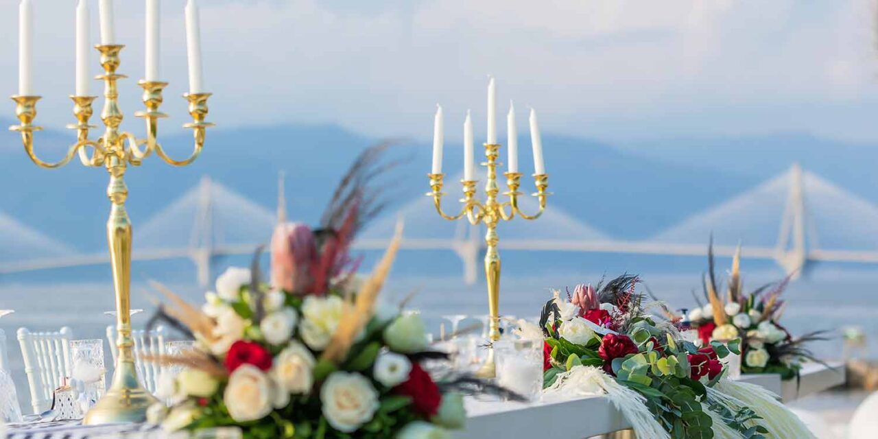 Gold candelabras surrounded by several flowers at a Great Gatsby Wedding by Rogdaki Events trademark