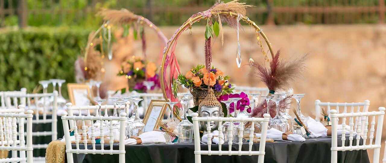 The circle of life decorated with pampas grass and natural roses used as a centerpiece alongside a gold urn and decorative Buddha figure inspired by the East culture by R