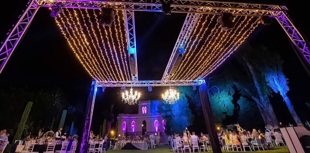 Τhe panoramic view of the private villa with fairy lights and crystal chandeliers giving magical lighting in the wedding ceremony by Rogdaki Events