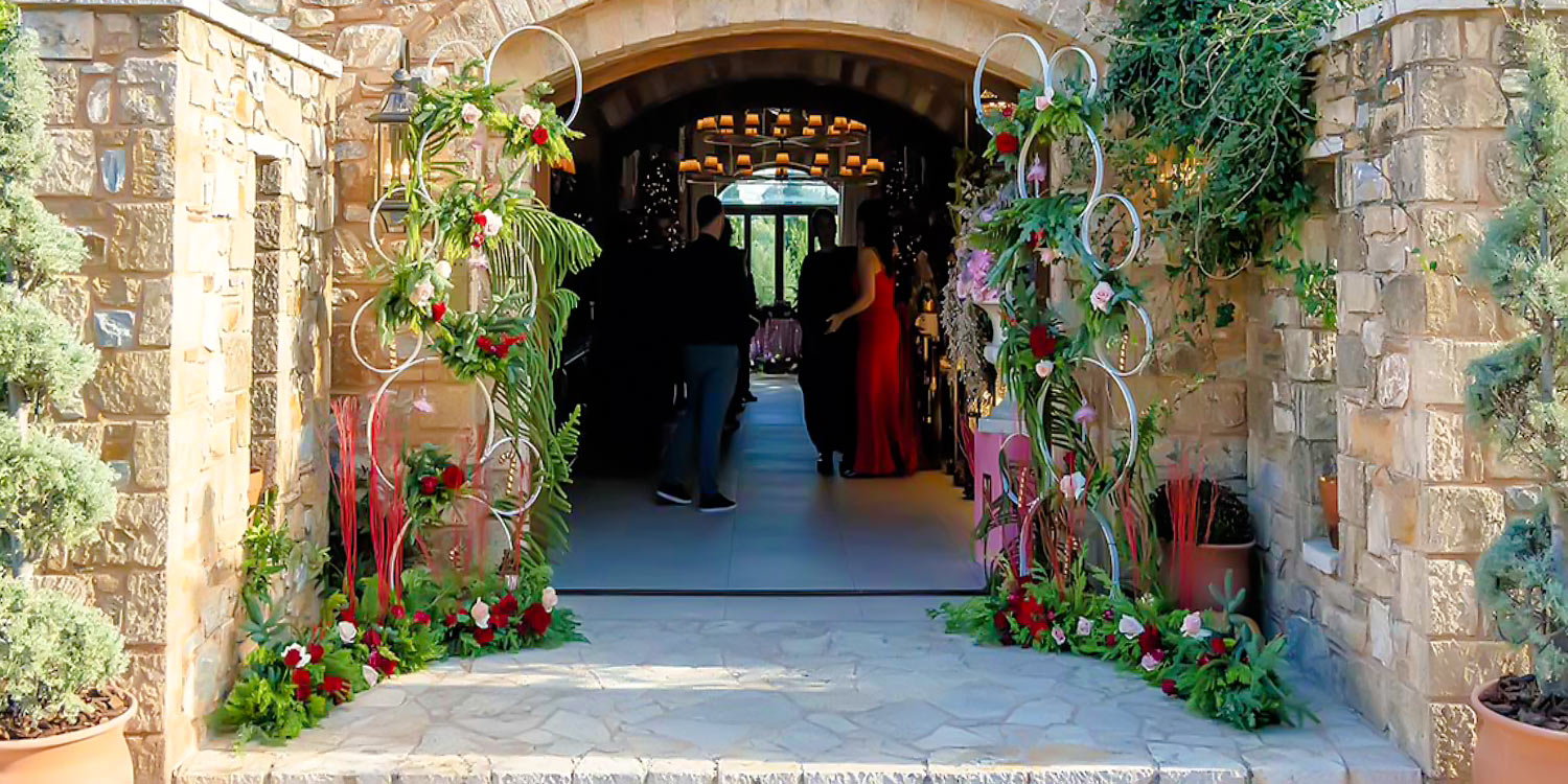 Μια Παραμυθένια Βάπτιση | Μπαλαρίνας & Καρυοθραύστη 7 A Magical Ballerina Rogdaki Events welcomes guests to a baptism at Pyrgos Petreza with a grand stone entrance adorned with floral arches creating a magical and festive atmosphere