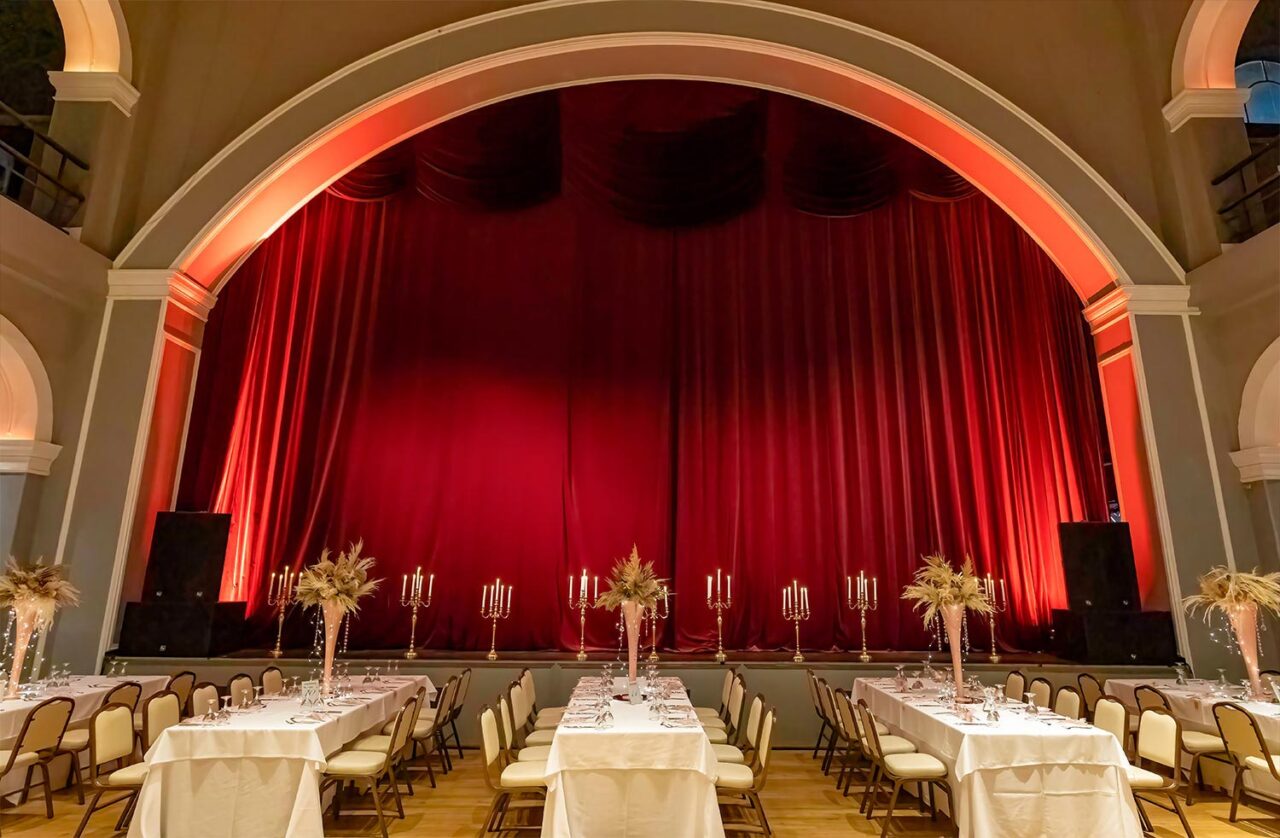 A Miracle Girl Baptism at Royal Theater — crimson velvet draws the curtain on a stage set for divine celebration.