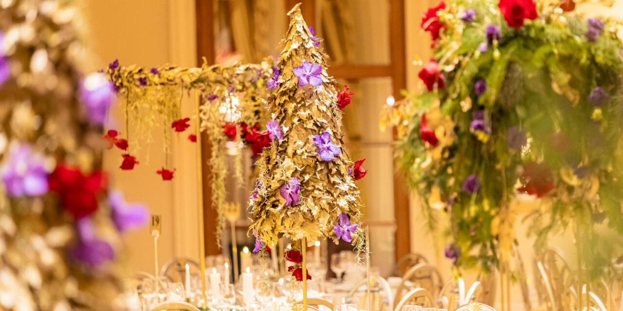 Golden tree centerpieces embellished with red roses and purple orchids by Rogdaki Events bring festive grandeur to the ballroom of the Grande Bretagne