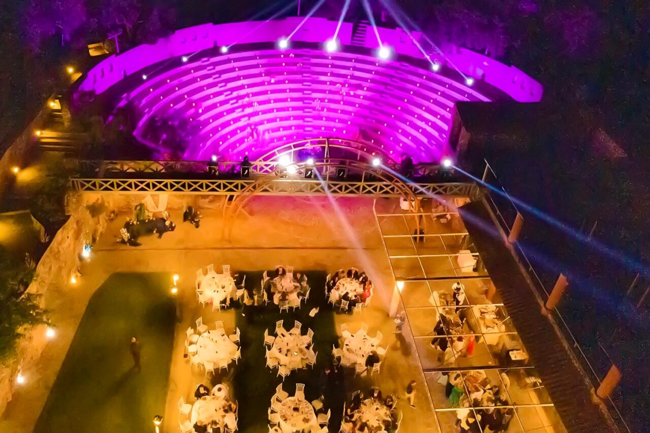 A majestic overview of the Ancient Greek Wedding in an Amphitheater by Rogdaki Events, showcasing candlelit tiers and elegant dinner tables in perfect harmony