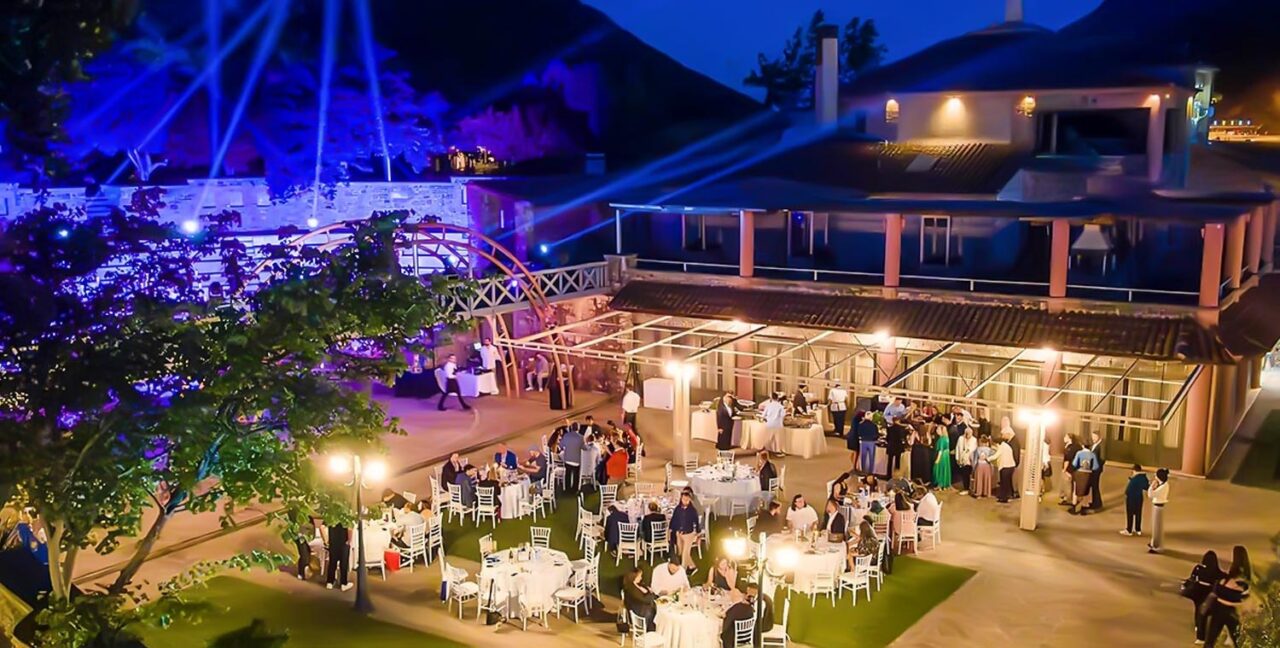 An enchanting Ancient Greek Wedding in an Amphitheater by Rogdaki Events, with guests dining under the stars, bathed in soft lighting and blue ambiance