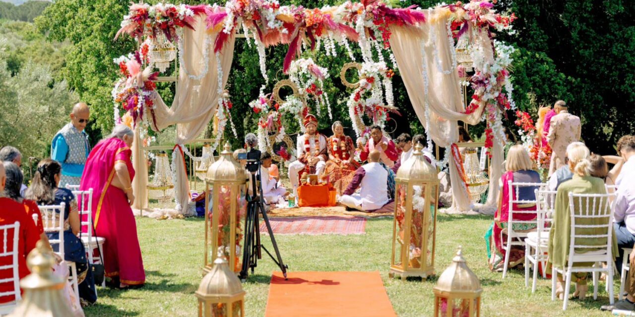 Indian Wedding in a Private Villa, by Rogdaki Events — bride and groom sit beneath a lavish mandap, surrounded by family, flowers, and blessings during sacred rituals