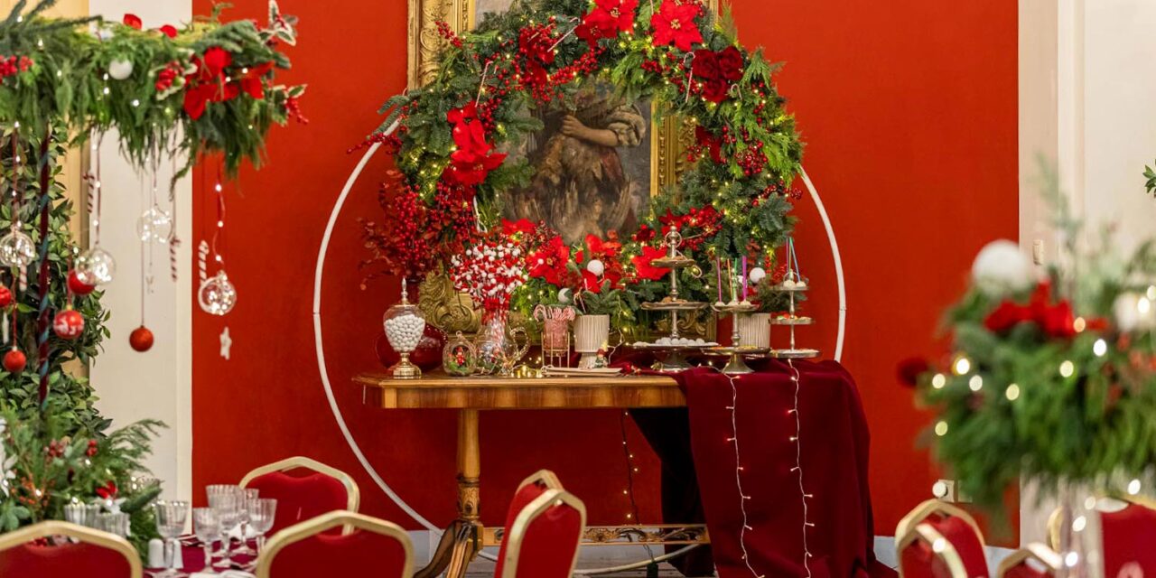 Rogdaki Events designs a festive dessert table with red poinsettias, Christmas wreath, and glowing lights for a luxury baptism