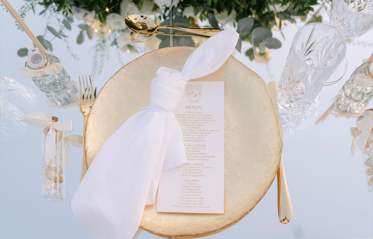 Exquisite gold accented table setting by Rogdaki Events for a Luxury Seaside Wedding in Greece