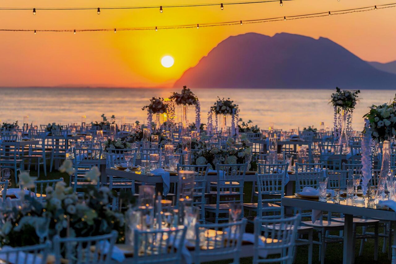 Reception tables illuminated by sunset at a Luxury Seaside Wedding in Greece, designed by Rogdaki Events