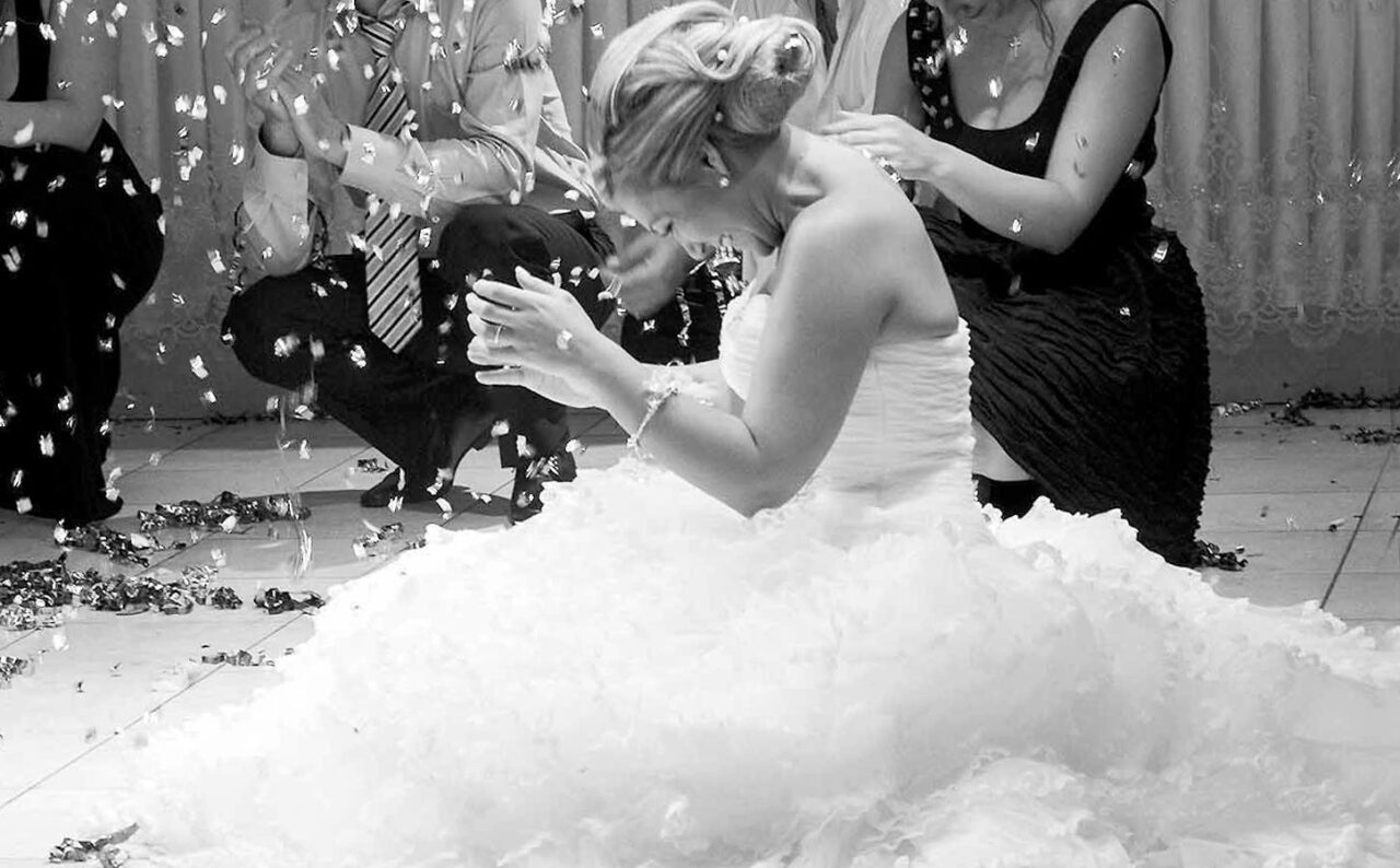 Fabulous Weddings in Greece 5 The bride enjoys a joyful moment surrounded by guests, reflecting the authentic spirit of Greek festivities by Rogdaki Events.