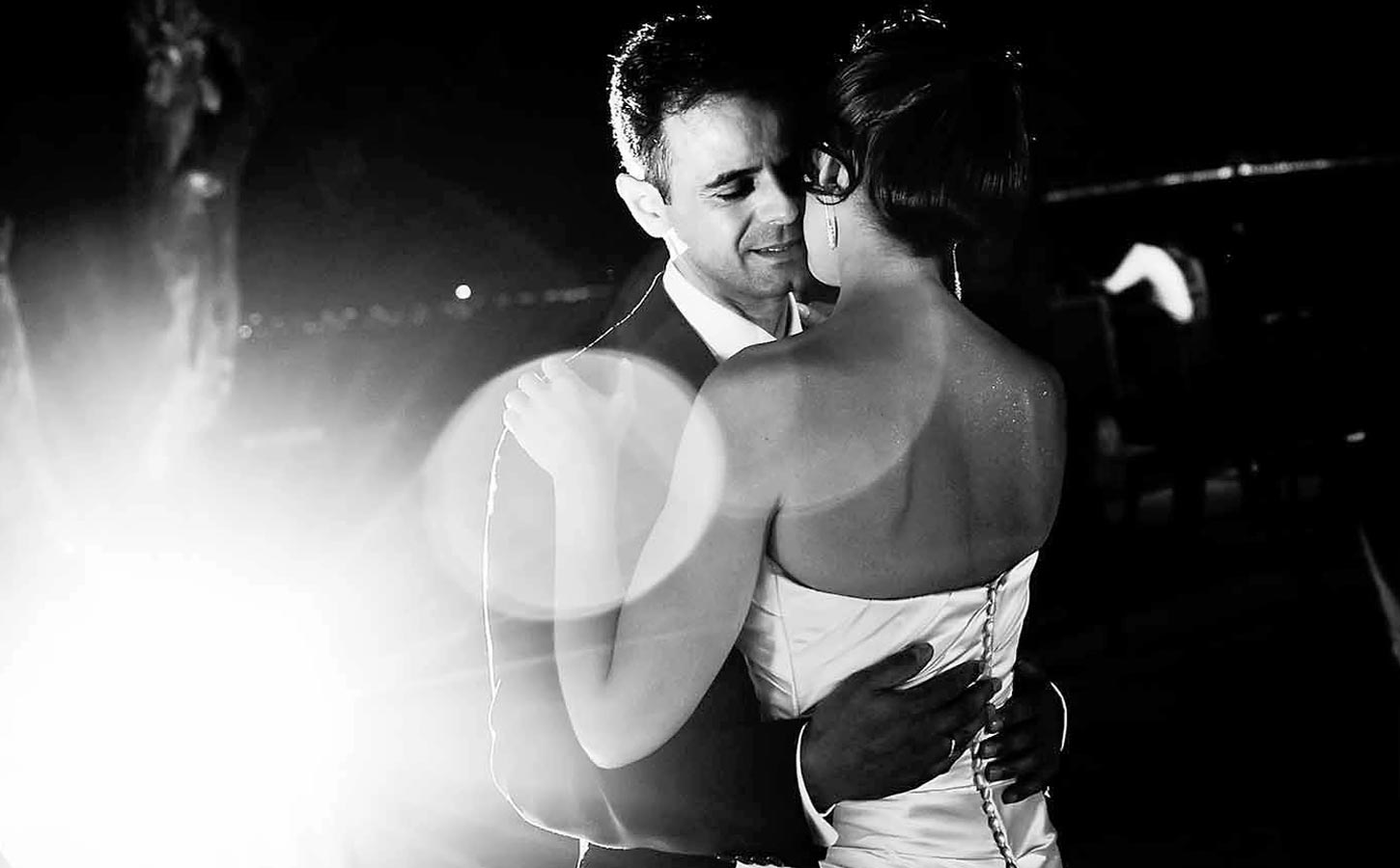 The newlyweds share their first dance, illuminated by subtle lighting in a timeless composition designed by Rogdaki Events.