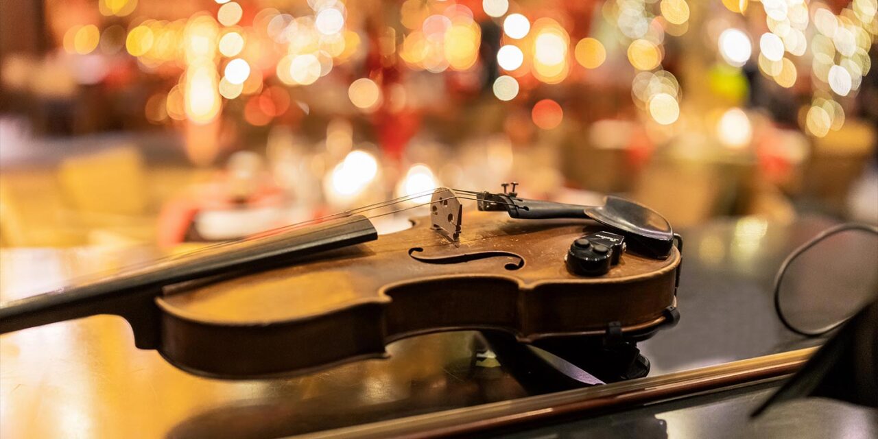 Μαγευτικός Χριστουγεννιάτικος Στολισμός Βάπτισης 29 Rogdaki Events, χριστουγεννιάτικη βάπτιση, Distinto, κοντινό σε βιολί πάνω σε τραπέζι με γιορτινό φόντο