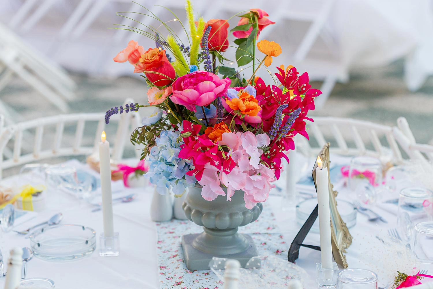 Chic & Colorful Γάμος στο Κτήμα Παναγιωτόπουλου 23 Rogdaki Events, κοντινό πλάνο μιας πολύχρωμης σύνθεσης λουλουδιών σε γκρι βάζο για μια εορταστική παραθαλάσσια δεξίωση.