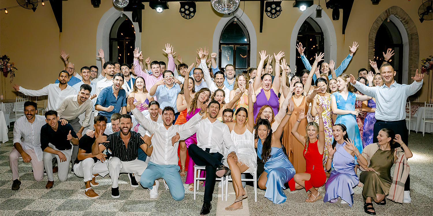 Chic & Colorful Γάμος στο Κτήμα Παναγιωτόπουλου 53 Rogdaki Events. Μια χαρούμενη ομαδική φωτογραφία καλεσμένων που ζητωκραυγάζουν και γιορτάζουν με το ζευγάρι