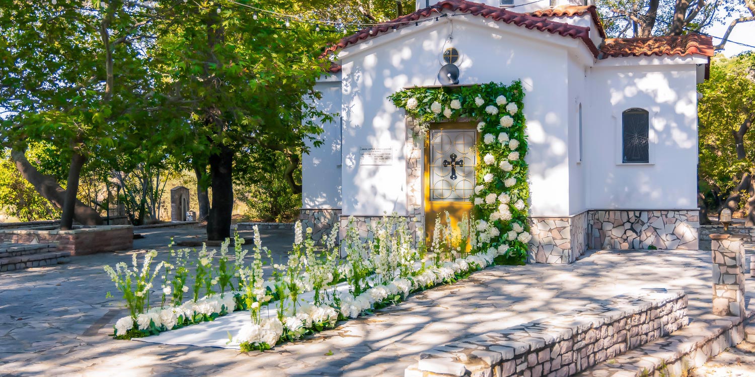 Ελληνικο-Γαλλικός Σικάτος Γάμος 2 Είσοδος του Αγίου Αναστασίου Δρεπάνου διακοσμημένη με λευκά άνθη, δημιουργία Rogdaki Events.
