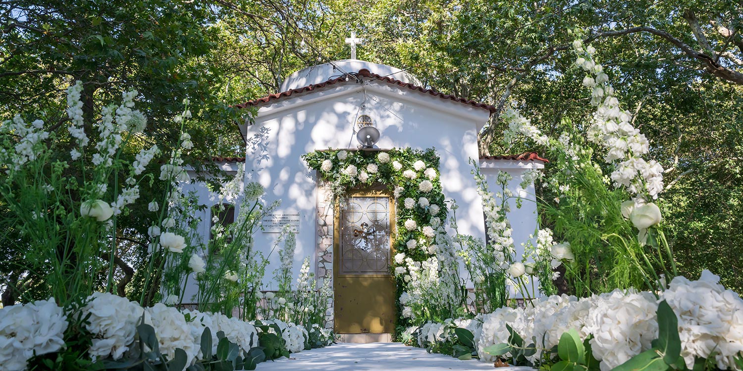 Ελληνικο-Γαλλικός Σικάτος Γάμος 1 Κομψή είσοδος νύφης με μονοπάτι στολισμένο με λευκά άνθη και παιώνιες στον Άγιο Αναστάσιο Δρεπάνου, διακοσμημένη από τη Rogdaki Events