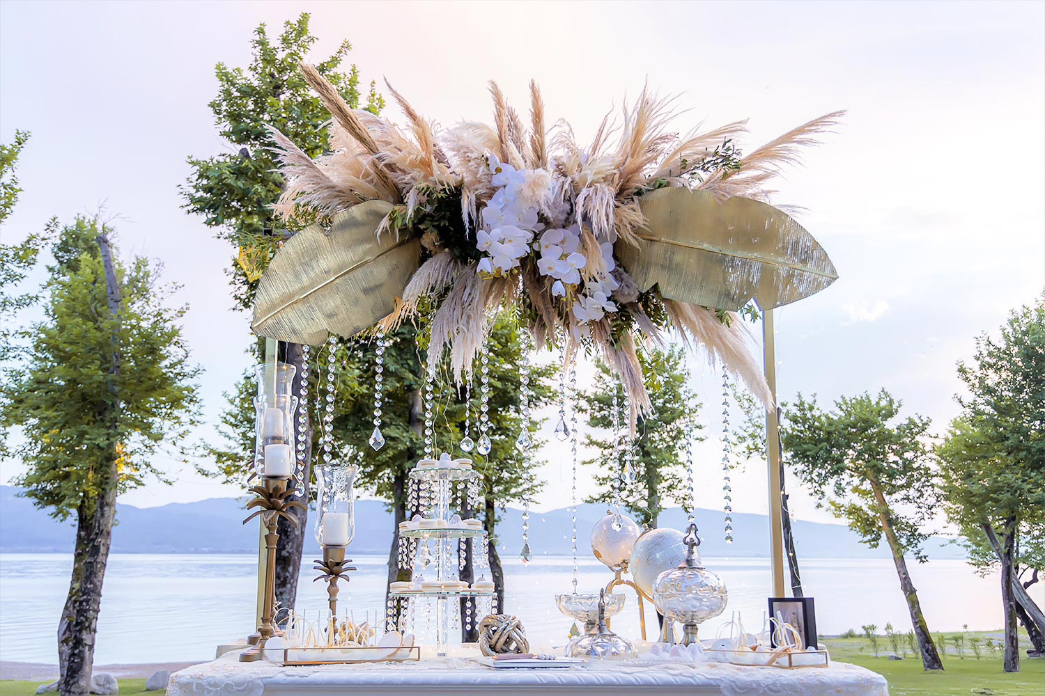 Trichonida Lake Wedding 18 Lake wedding at Pythari by Rogdaki Events—golden leaves, orchids, and crystal strands over a serene lakeside table