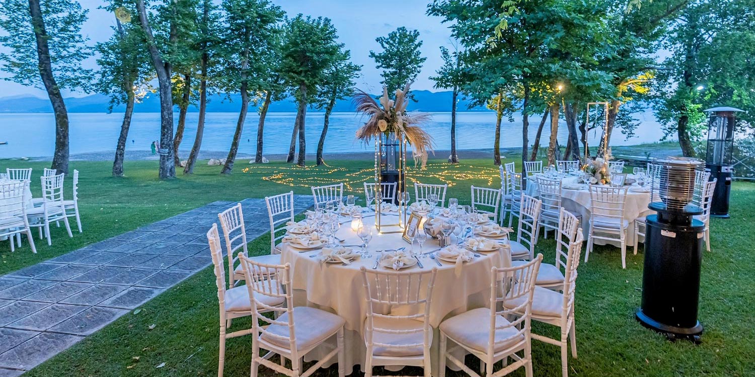 Trichonida Lake Wedding 29 Lake wedding at Pythari by Rogdaki Events—string lit lawn, white tables, and serene lakeside elegance under the stars