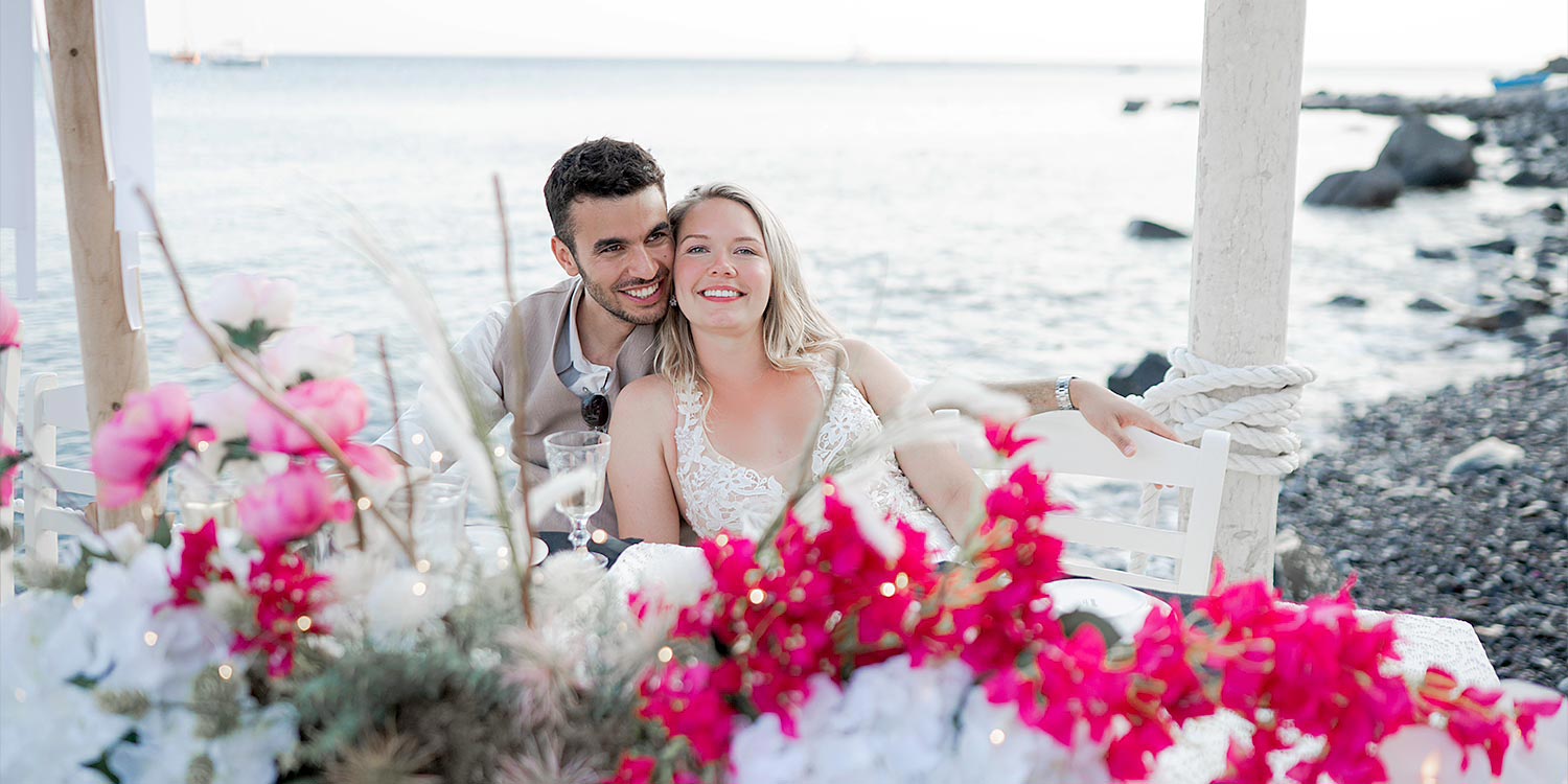 Γάμος σε Ταβέρνα στη Σαντορίνη 22 Rogdaki Events, Το ζευγάρι ποζάρει μπροστά στις φούξια βουκαμβίλιες σε παραδοσιακή ταβέρνα στη Σαντορίνη