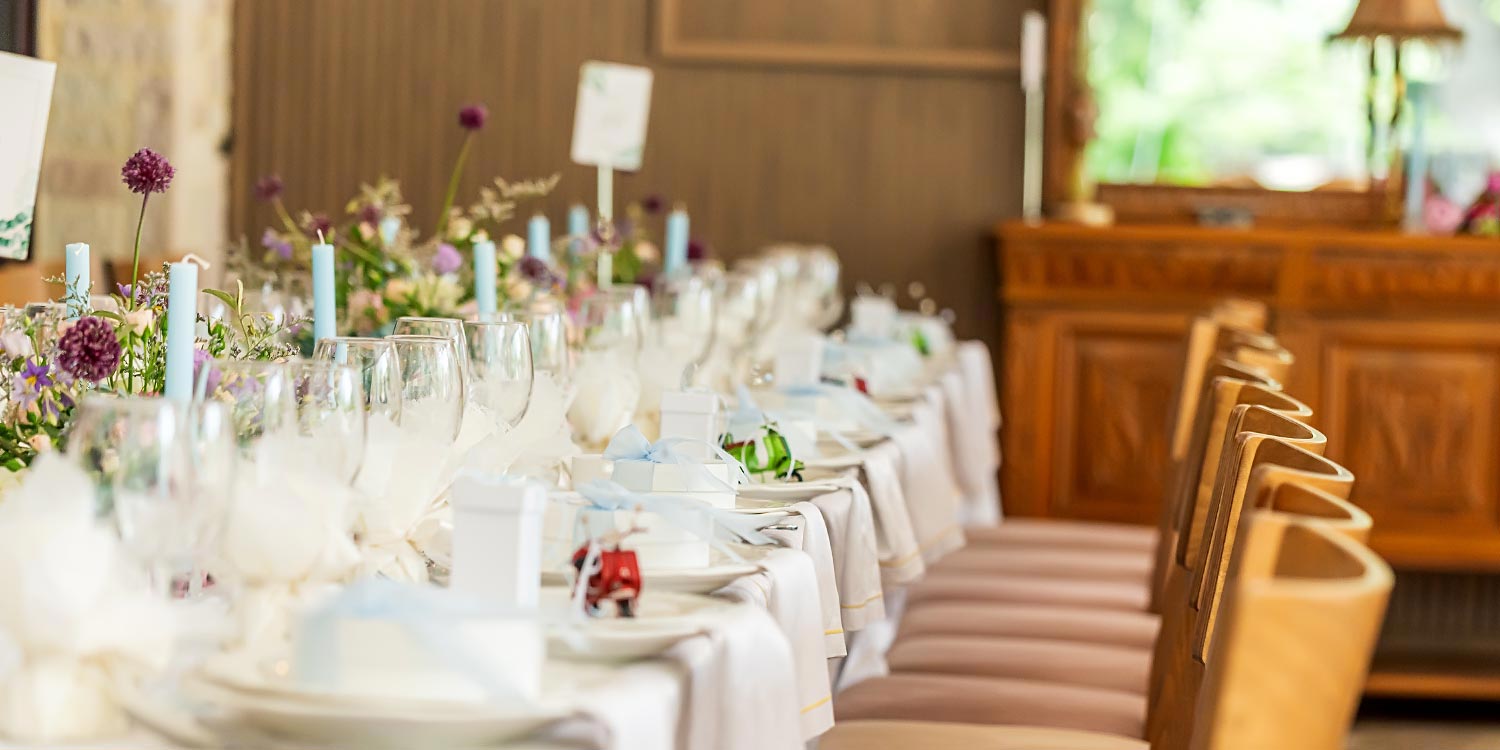 A Signature Wedding & Baptism Production in Blue 16 Wedding at Korali, Agrinio, with Rogdaki Events decor featuring a long banquet table, white dinnerware, blue candles, and pastel florals.