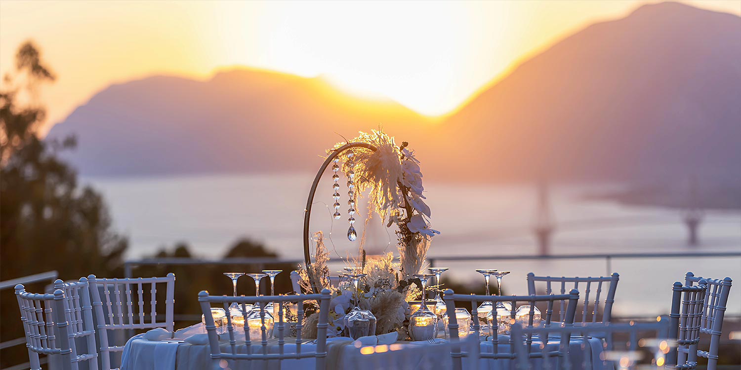 Ελληνικο-Γαλλικός Σικάτος Γάμος 24 ρυσό ηλιοβασίλεμα πίσω από floral διακόσμηση της Rogdaki Events στο Ηδύλοφον