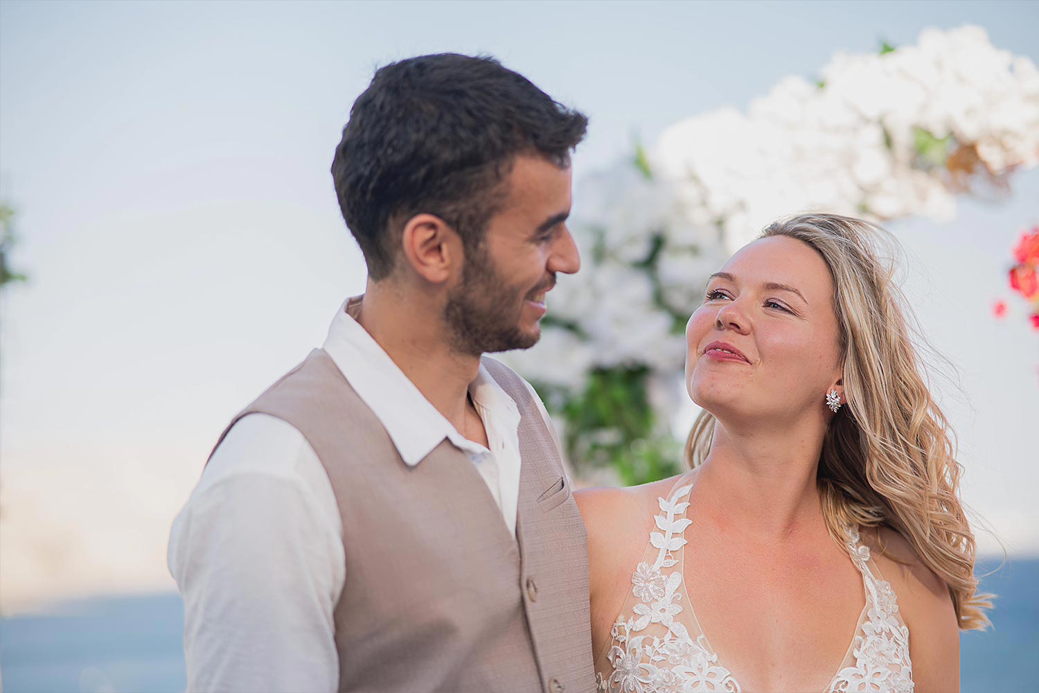 Γάμος σε Ταβέρνα στη Σαντορίνη 5 Γάμος στη Σαντορίνη με Rogdaki Events, βλέμμα αγάπης κάτω από ανθισμένο παραθαλάσσιο σκηνικό