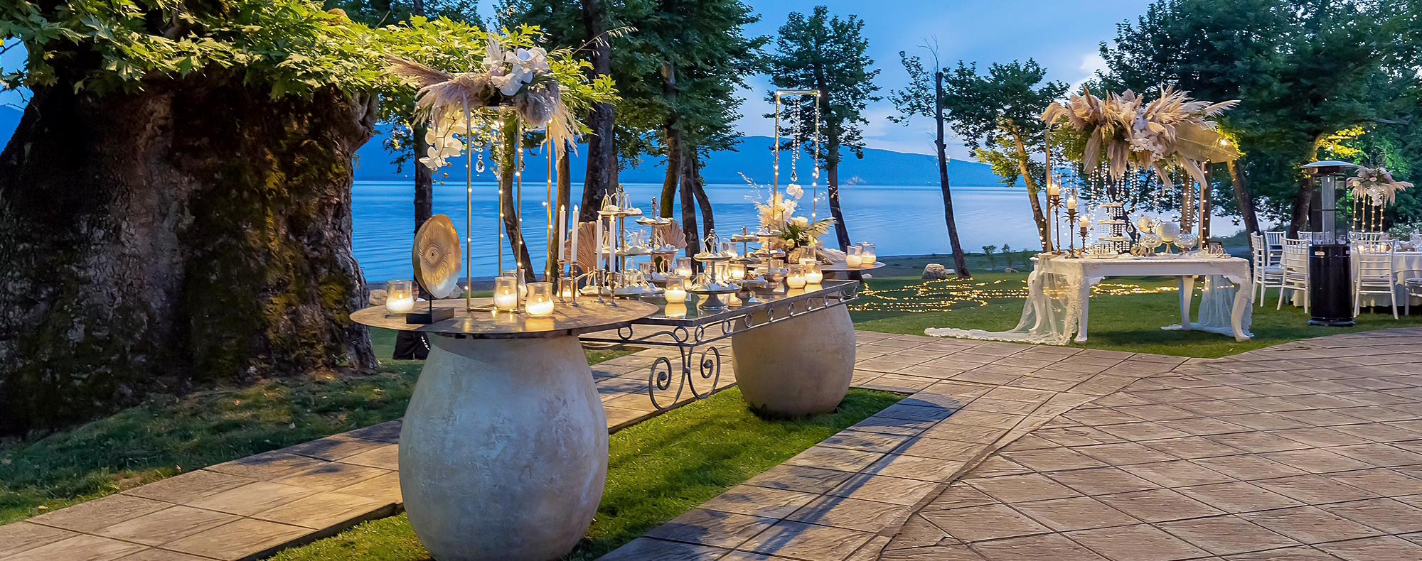 Γάμος στη λίμνη (Πυθάρι) από τη Rogdaki Events με τραπέζια στολισμένα με κεριά, χρυσές ανθοσυνθέσεις