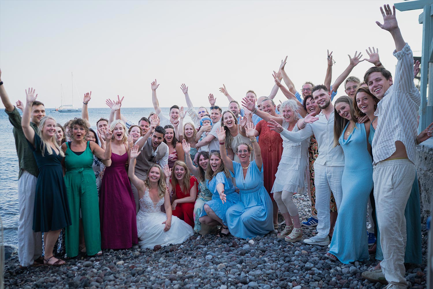 Γάμος σε Ταβέρνα στη Σαντορίνη 26 Καλεσμένοι και ζευγάρι σε μια αναμνηστική φωτογραφία από τον γάμο της Rogdaki Events σε παραθαλάσσια ταβέρνα στη Σαντορίνη