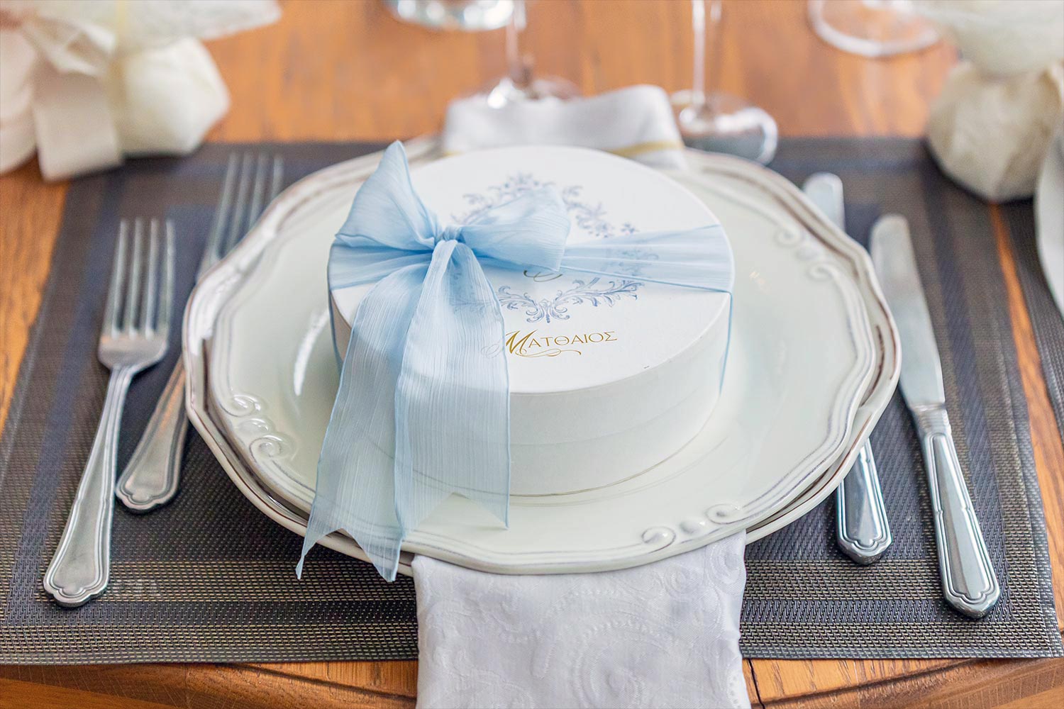 Γάμος και βάπτιση στο Αγρίνιο με μοντέρνο ύφος 18 Μπομπονιέρα Ματθαίος σε λευκό πιάτο, με γαλάζια κορδέλα και διακόσμηση Rogdaki Events στο Κοράλι, Αγρίνιο