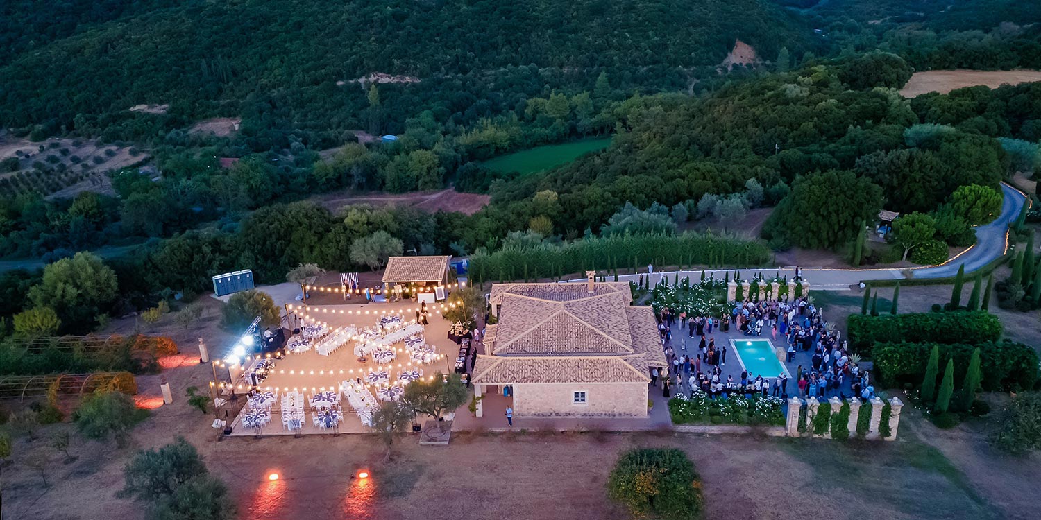 Οργάνωση γάμου Rogdaki Events, Αεροφωτογραφία πολυτελούς κτήματος με φωτισμένη δεξίωση και πισίνα σε φυσικό τοπίο
