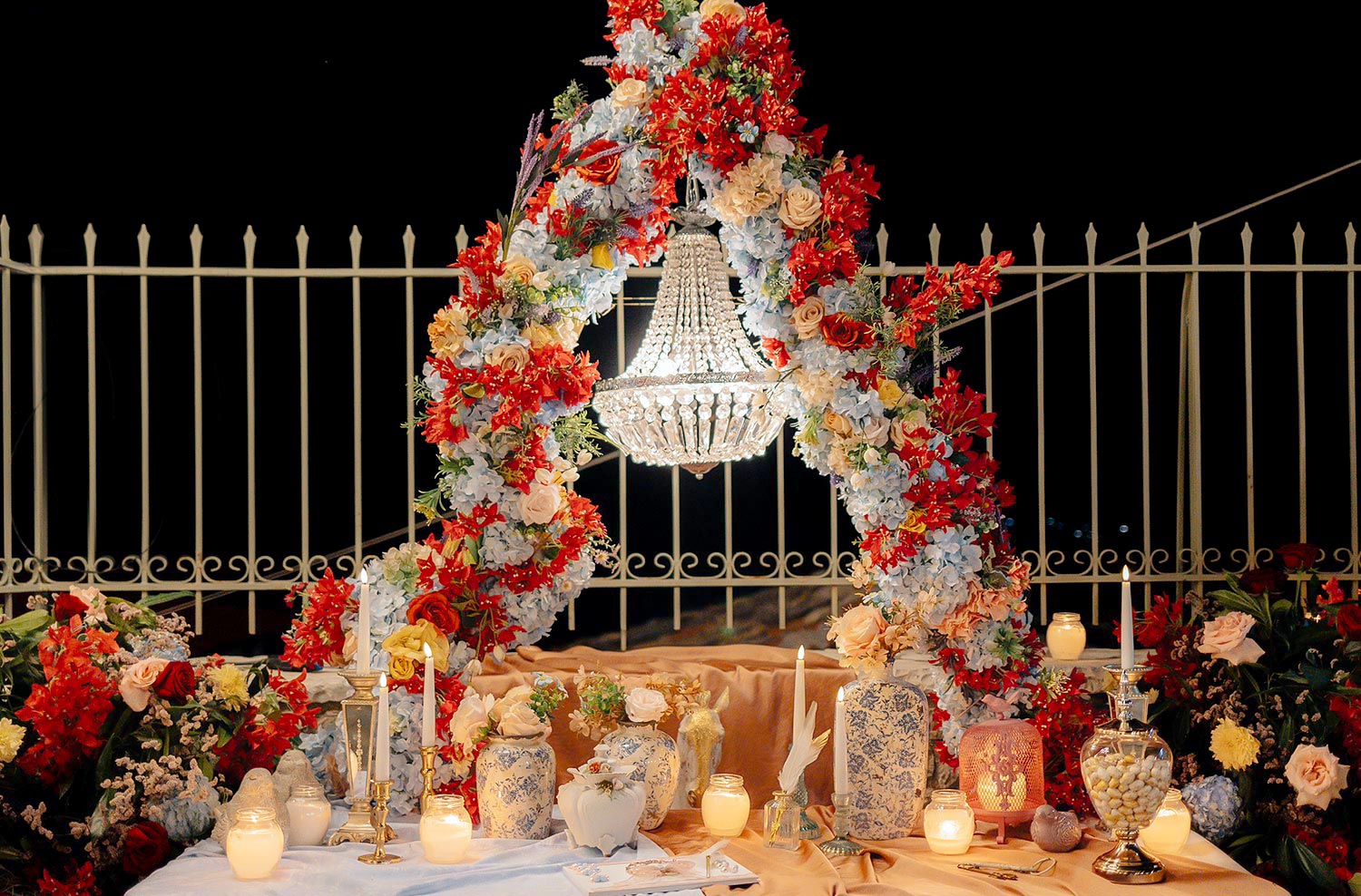 A crystal chandelier glows within a floral arch for this Rogdaki Events Authentic Village Square Wedding.