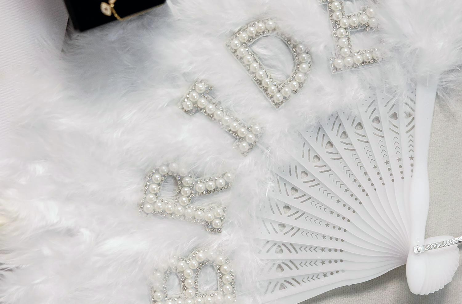 A Bridgerton Wedding in Greece 3 A white feathered fan featuring BRIDE spelled in pearls for this wedding