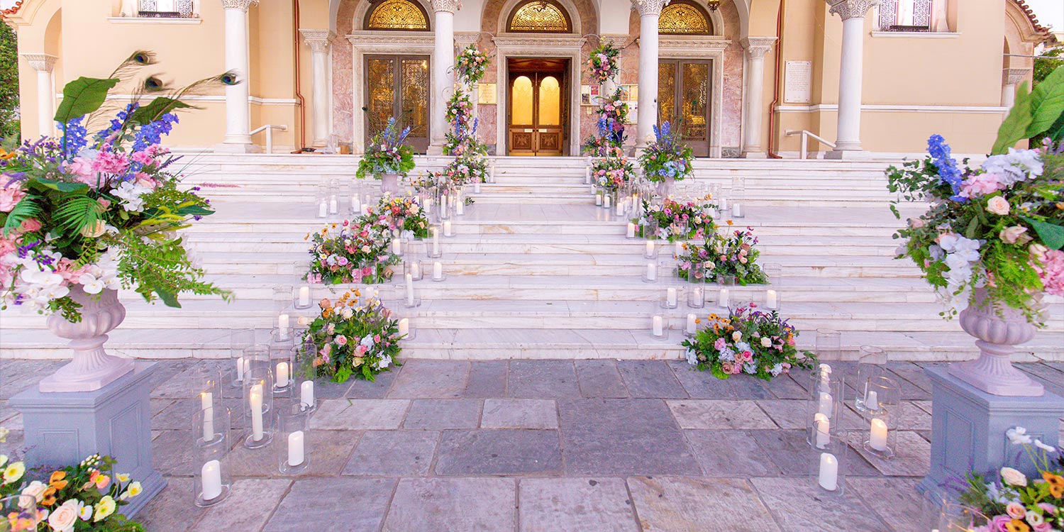 A Bridgerton Wedding in Greece 18 Floral arrangements and candles decorating the stairs of Saint Andrew church for the Rogdaki Events Wedding