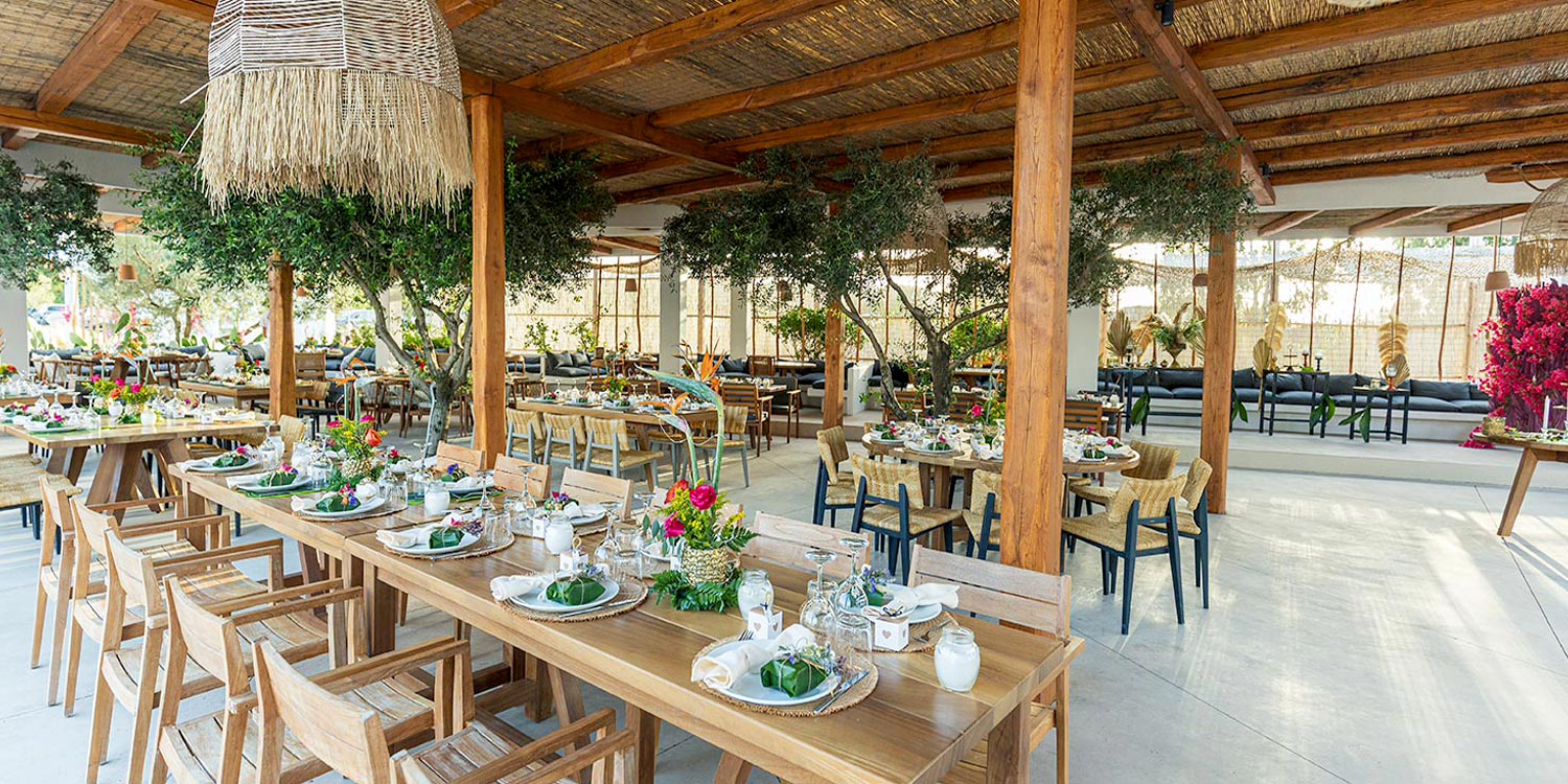 Open‑air ONA setting styled by Rogdaki Events with warm textures, florals, and relaxed island elegance.