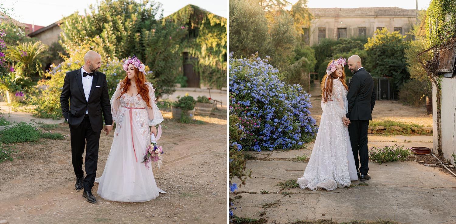A Bridgerton Wedding in Greece 56 The couple walks hand in hand through a picturesque, rustic landscape featuring stone buildings and blooming gardens, enjoying the magic of their post wedding photoshoot.