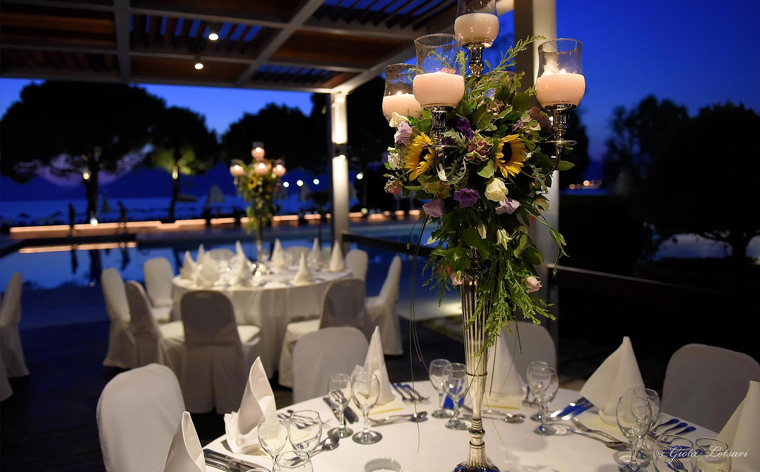 Στολισμός Εταιρικής Εκδήλωσης για τα 130 Χρόνια της Εφημερίδας «Πελοπόννησος» 16 Επιβλητικό ασημένιο κηροπήγιο διακοσμημένο με ηλιοτρόπια και μωβ λυσίανθο, σχεδιασμένο από την Άννα Μαρία Ρογδάκη