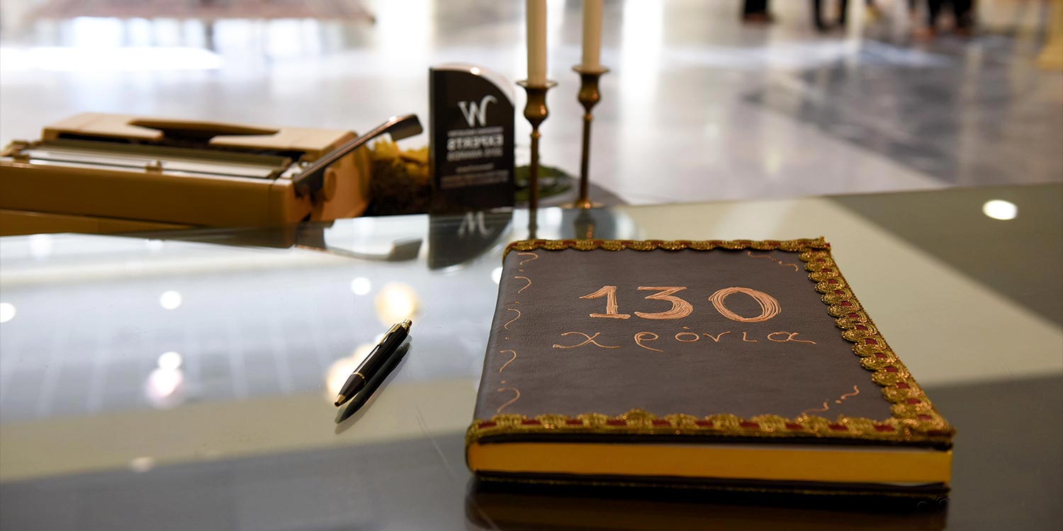 Στολισμός Εταιρικής Εκδήλωσης για τα 130 Χρόνια της Εφημερίδας «Πελοπόννησος» 1 Λεπτομέρεια από το χειροποίητο βιβλίο ευχών 130 Χρόνια Πελοπόννησος σε γυάλινο τραπέζι από την Rogdaki Events Trademark.